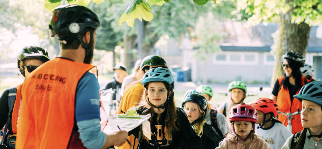 A bike education instructor talks to a group of students ready to participate in a bike bus.