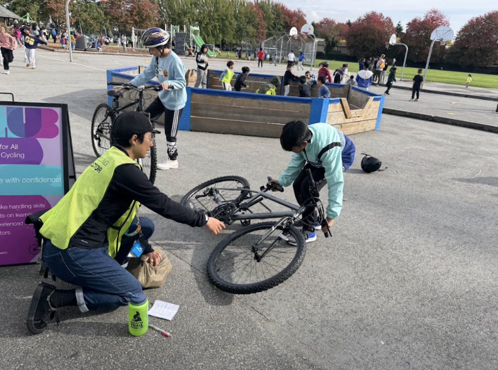 An instructor inspects a bike with a student.