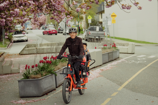 A man and his two children ride their cargo bike on a separated cycling path.