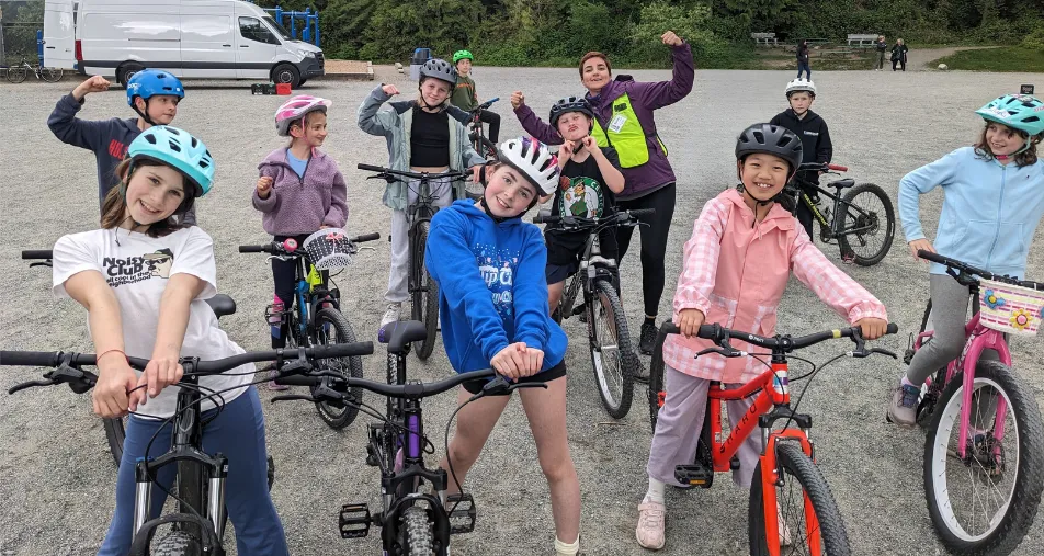 Students pose for a silly photo with bikes on a gravel field.