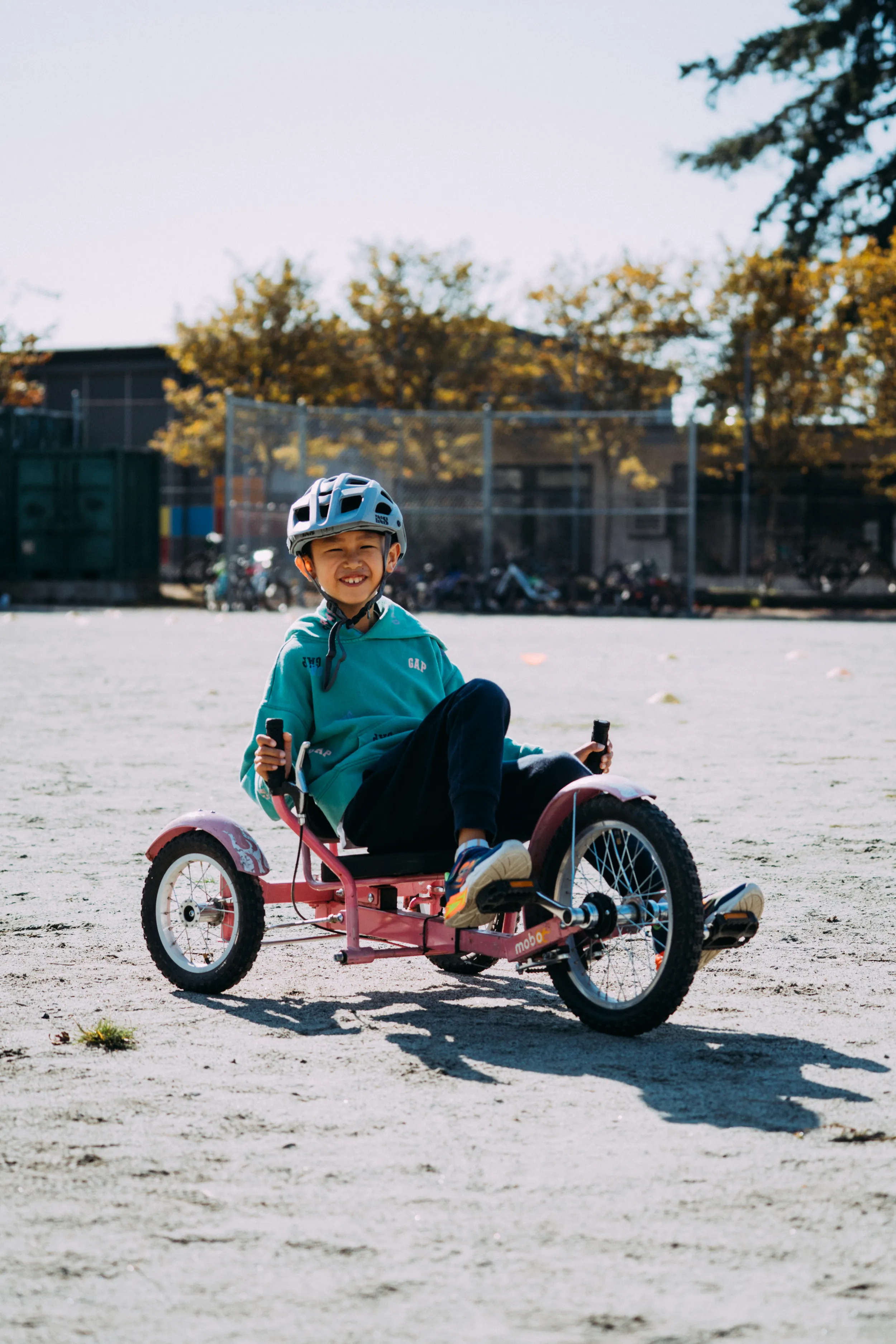 A boy rides an adaptive bike on school grounds.