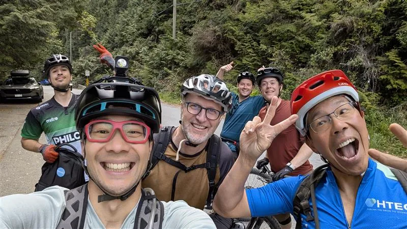 A group of colleagues pose for a photo with their mountain bikes.