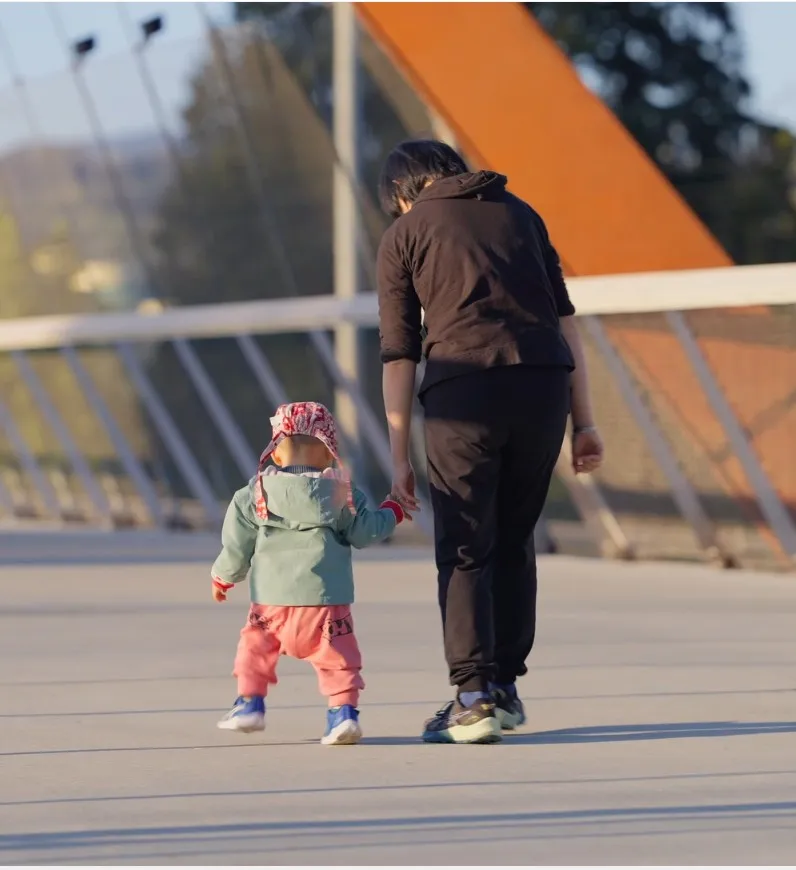 A parent holds the hand of their toddler as they walk over the new Burnaby Lake Overpass.
