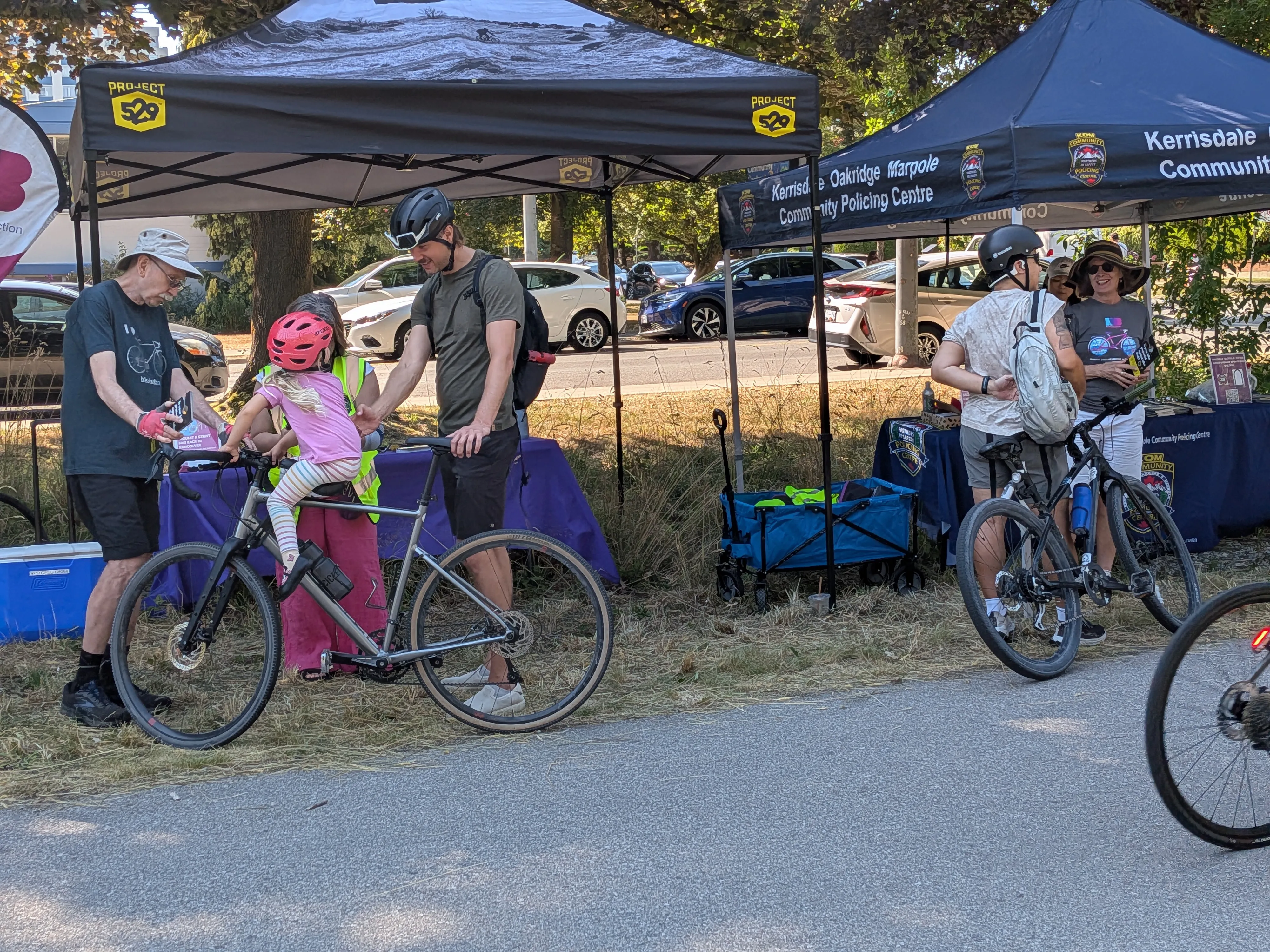 Several people gather around pop-up tents to register their bikes with Project 529 during HUB Cycling's bike parking summer pop-ups.